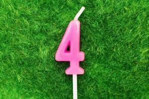 candle in the form of number 4 on the green grass background, a place for a greeting text photo