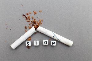 broken cigarette with the word stop on gray background close. stop smoking concept photo