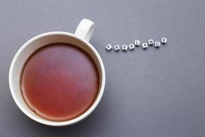 una taza de té y una palabra independiente hecha de cubos de plástico de cuentas sobre fondo gris con espacio para copiar foto