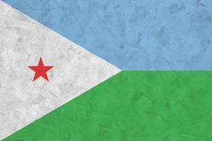 Djibouti flag depicted in bright paint colors on old relief plastering wall. Textured banner on rough background photo