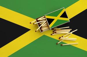 Jamaica flag is shown on an open matchbox, from which several matches fall and lies on a large flag photo