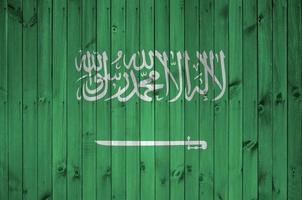 Saudi Arabia flag depicted in bright paint colors on old wooden wall. Textured banner on rough background photo