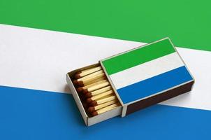 Sierra Leone flag is shown in an open matchbox, which is filled with matches and lies on a large flag photo