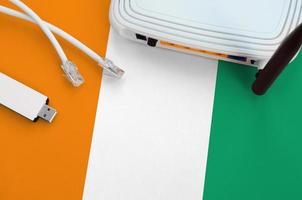 Ivory Coast flag depicted on table with internet rj45 cable, wireless usb wifi adapter and router. Internet connection concept photo