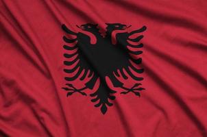 Albania flag is depicted on a sports cloth fabric with many folds. Sport team banner photo