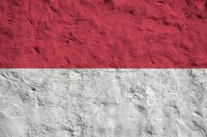 Indonesia flag depicted in bright paint colors on old relief plastering wall. Textured banner on rough background photo