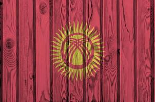 Kyrgyzstan flag depicted in bright paint colors on old wooden wall. Textured banner on rough background photo