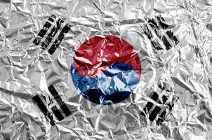 South Korea flag depicted in paint colors on shiny crumpled aluminium foil closeup. Textured banner on rough background photo