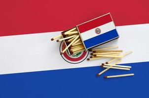 Paraguay flag is shown on an open matchbox, from which several matches fall and lies on a large flag photo