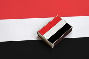 Yemen flag is pictured on a matchbox that lies on a large flag photo