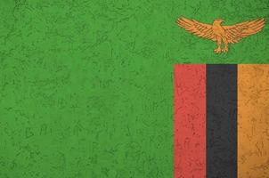 Zambia flag depicted in bright paint colors on old relief plastering wall. Textured banner on rough background photo