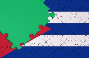 Cuba flag is depicted on a completed jigsaw puzzle with free green copy space on the left side photo