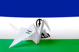 Lesotho flag depicted on paper origami crane wing. Handmade arts concept photo