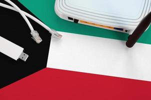 bandera de kuwait representada en la mesa con cable de internet rj45, adaptador wifi usb inalámbrico y enrutador. concepto de conexión a internet foto