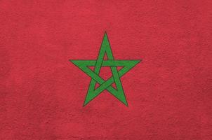 Morocco flag depicted in bright paint colors on old relief plastering wall. Textured banner on rough background photo