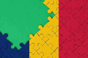 Chad flag is depicted on a completed jigsaw puzzle with free green copy space on the left side photo