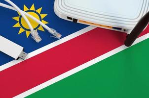 bandera de namibia representada en la mesa con cable de internet rj45, adaptador wifi usb inalámbrico y enrutador. concepto de conexión a internet foto