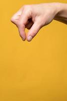 Woman hand shows with her fingers as if she is taking or holding an invisible thing. Copy space. Isolated, on a yellow background. photo