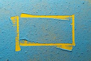 Imprint of a yellow irregular frame on a bright blue powder. Copy space. Abstract background. Top view. photo