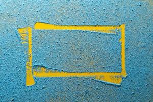 Imprint of a yellow irregular frame on a bright blue powder. Copy space. Abstract background. Top view. photo