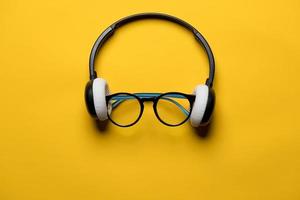 Headphones and glasses look like a face on a yellow background. Musical concept. Top view. photo