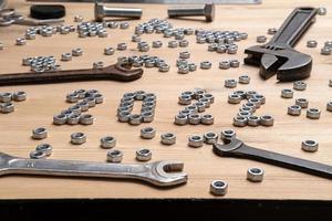 Number 2022 is lined with metal nuts on a wooden table next to a variety of wrenches and bolts. Concept of preparing for the New Year. photo