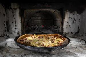 Deliciosa y apetitosa pizza cocinada a la brasa en un antiguo horno ruso. cocina tradicional del país. estilo de vida. foto