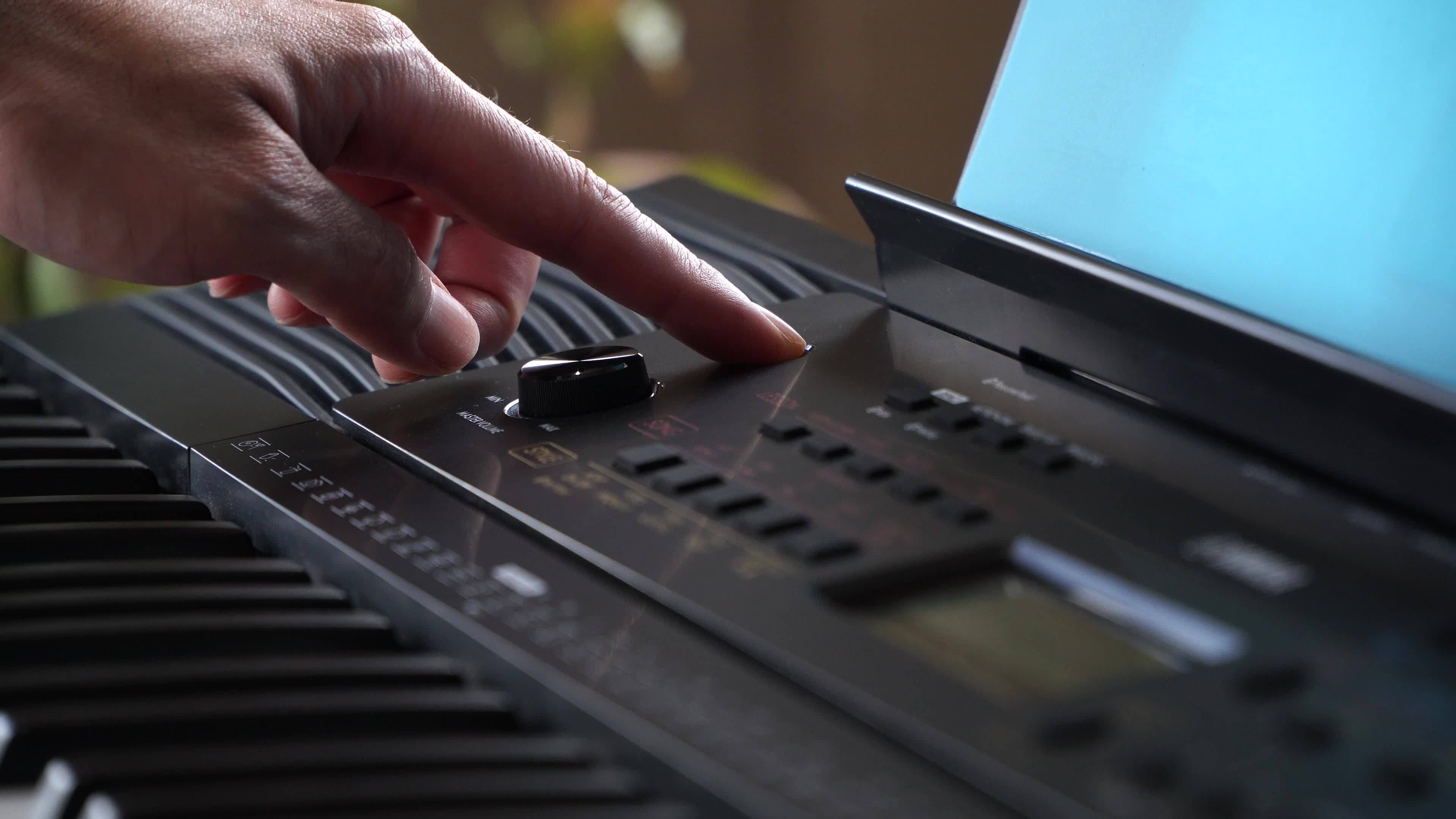 Man playing electronic music keyboard synthesizer with hands adding