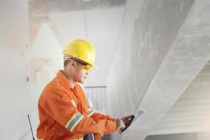 ingeniero o capataz sosteniendo una tableta. sitio de ingeniería de detalles de trabajo y trabajo con concepto de tecnología. foto