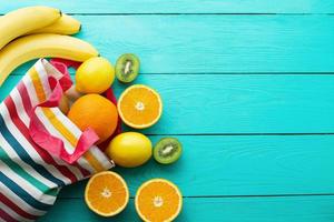 Summer fun time and fruits on blue wooden background. Mock up and picturesque. Orange, lemon, kiwi, banana fruit on table. Top view and mock up photo