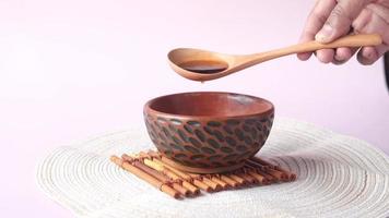 Wooden spoon pouring tea into decorative wood bowl video