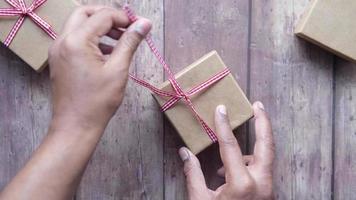 Overhead view of untying a red ribbon to open small brown gift box video