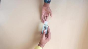 Sharing hand sanitizer across a table overhead view video