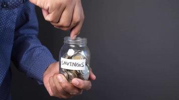 Adult man adds coins to savings jar video