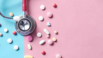 Stethoscope and pills on pink and blue background