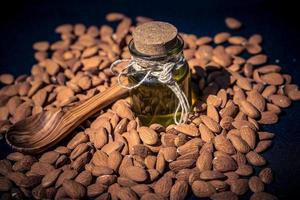 a pile of almonds and a glas with almond oil photo