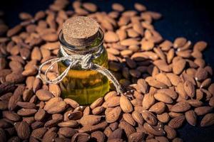 un montón de almendras y un vaso con aceite de almendras foto