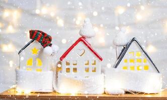 Cozy house is wrapped in a hat and scarf in a snowstorm -window sill decor. Winter, snow - home insulation, protection from cold and bad weather, room heating system. Festive mood, Christmas, New Year photo