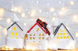 la acogedora casa está envuelta en un sombrero y una bufanda en una tormenta de nieve -decoración del alféizar de la ventana. invierno, nieve: aislamiento del hogar, protección contra el frío y el mal tiempo, sistema de calefacción de habitaciones. estado de ánimo festivo, navidad, año nuevo foto