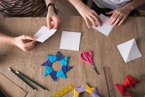 mom and daughter make origami from colored paper on self-isolation photo