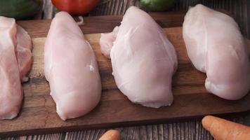 Raw chicken breasts on wood cutting board with vegetables around video