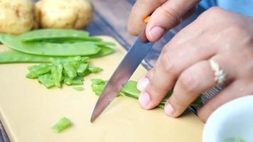 Slicing green peas on plastic cutting board, close up video