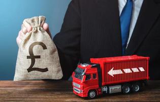 Businessman with british pound sterling money bag and truck. Good salaries for drivers. Rising prices, global containers shortage crisis. Logistics. High income of the transport business photo