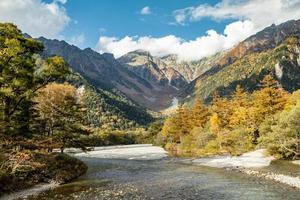 Beautiful background of the center of Kamikochi national park by snow mountains, rocks, and Azusa rivers from hills covered with leaf change color during the Fall Foliage season. photo