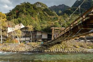 turistas no identificados disfrutan en el puente kappa bashi en el área del punto central del parque nacional kamikochi, nagano, japón durante la temporada de follaje de otoño. foto