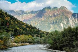 hermoso fondo del centro del parque nacional kamikochi por montañas nevadas, rocas y ríos azusa desde colinas cubiertas de hojas que cambian de color durante la temporada de follaje de otoño. foto