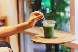 concepto de dieta saludable mujer bebiendo batido verde en la cafetería. foto