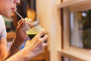 Woman drinking an organic green smoothie in cafe. photo