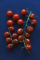 Small cherry tomatoes are yellow and red in a paper container. Small tomatoes on a black background. photo