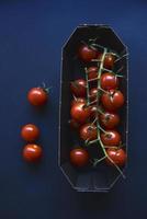 Small cherry tomatoes are yellow and red in a paper container. Small tomatoes on a black background. photo